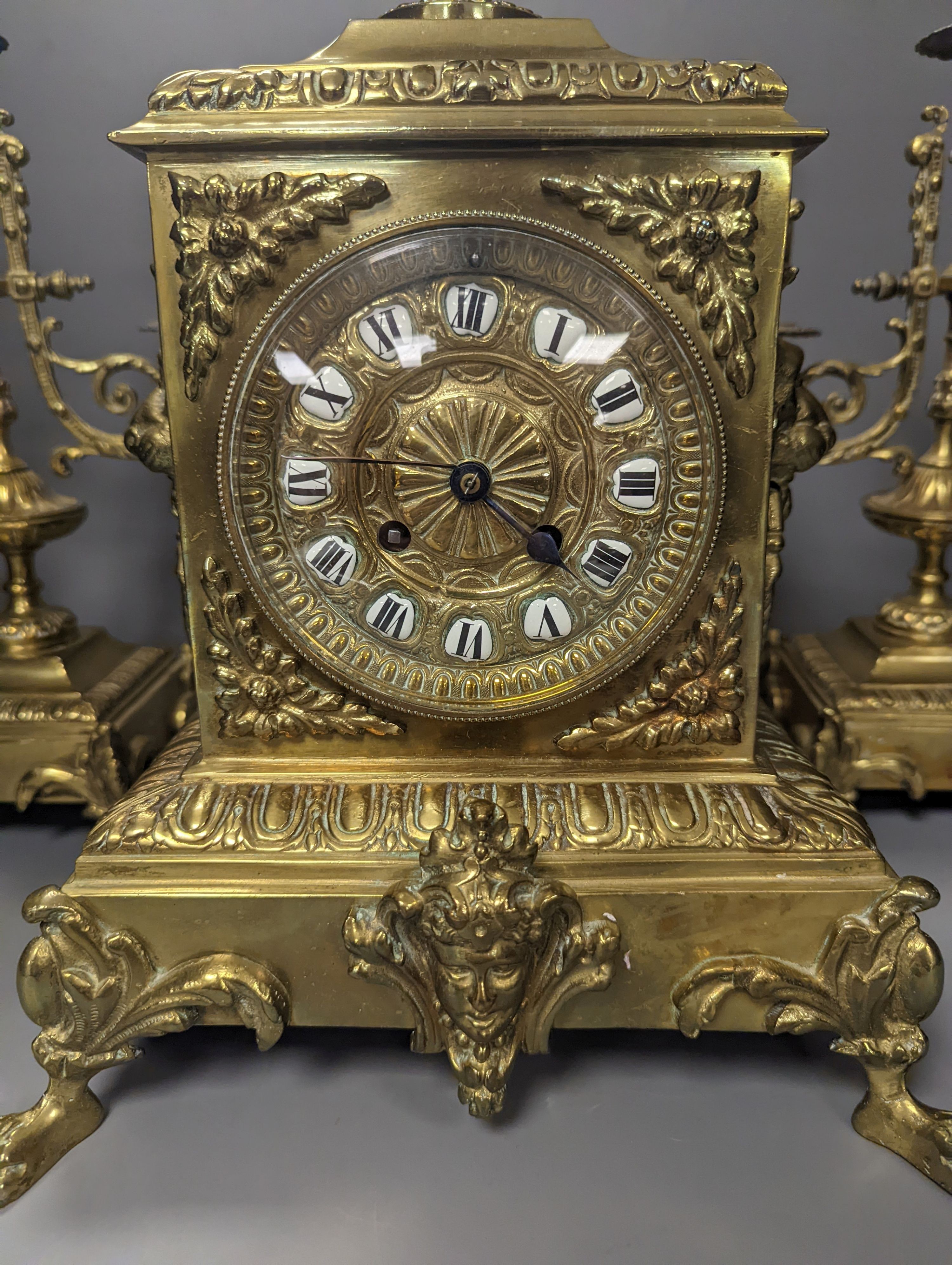 A 19th century French ornate brass clock garniture including a pair of 3 branch candelabra, Clock 42 cms high.